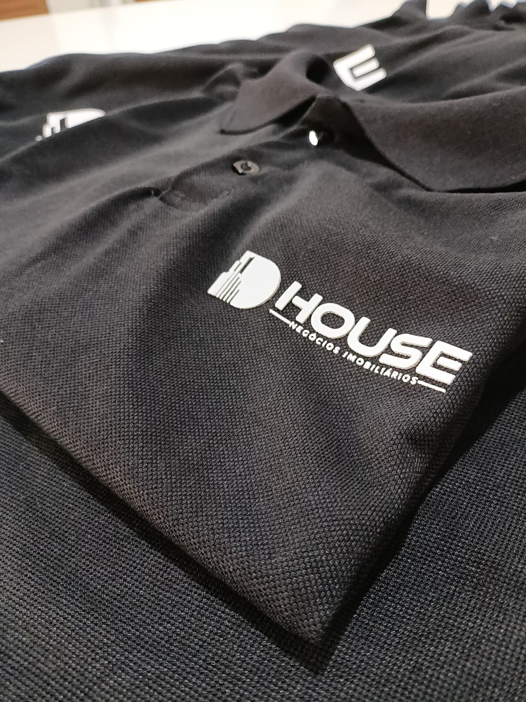 Polo preta com a estampa da House Negócios Imobiliários